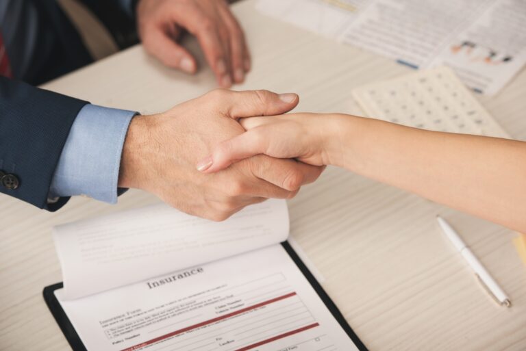 woman shaking insurance adjuster's hand over insurance policy